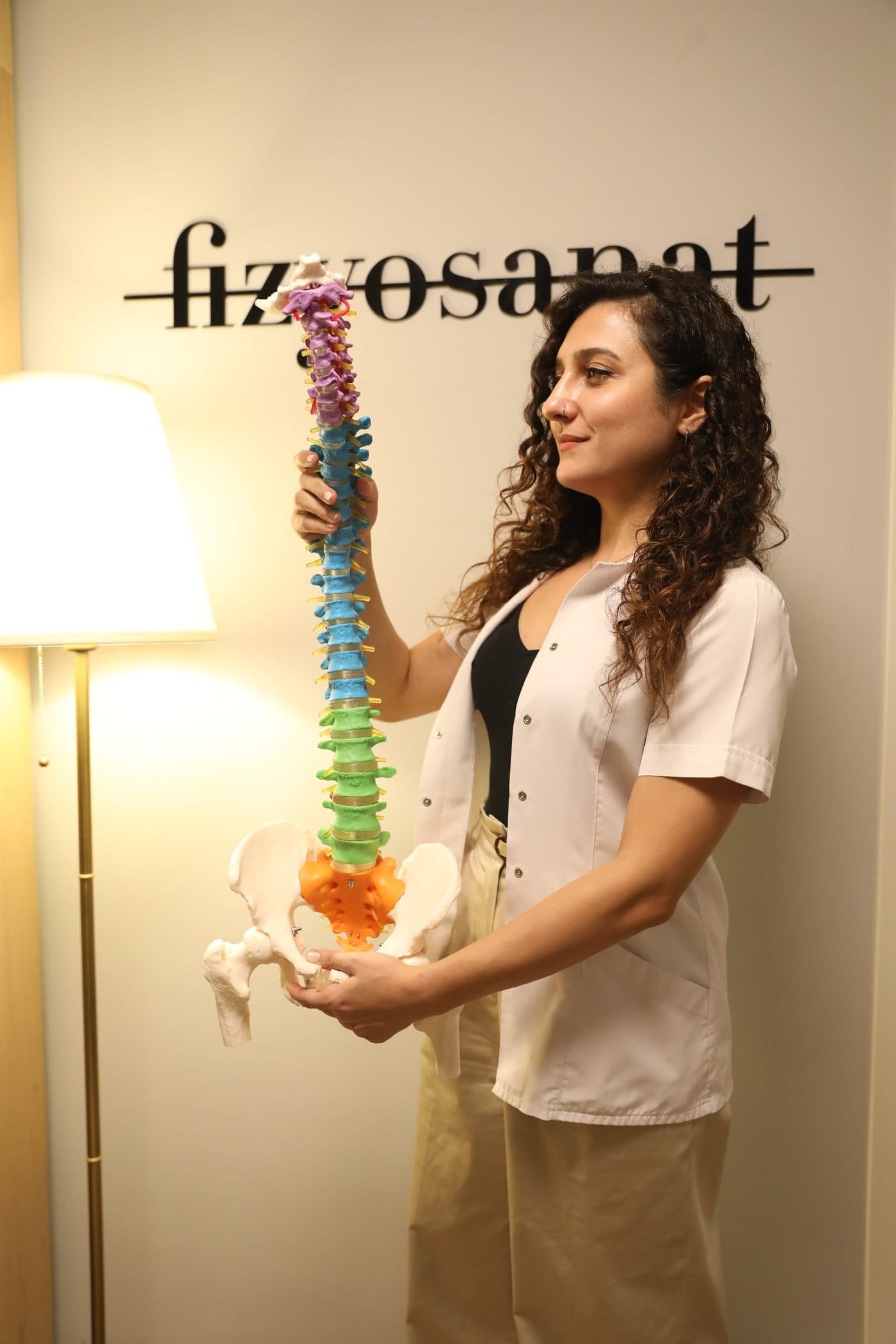 Uzm. Fzt. Osteopat Asude Özkaya, elinde omurga modeliyle